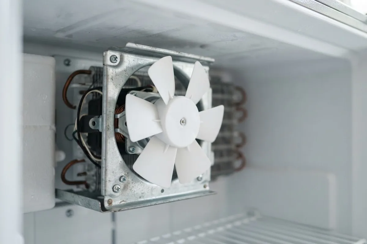 Close-up view of an evaporator freezer fan making noise due to frost buildup near the motor assembly